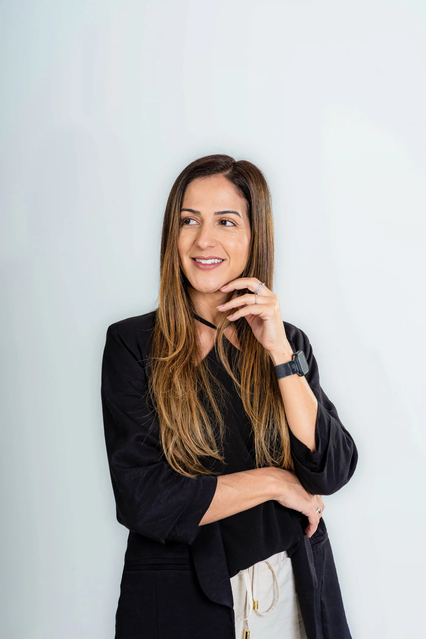 Letícia Canedo, de blusa preta, apoiando a mão no queixo em atitude reflexiva
