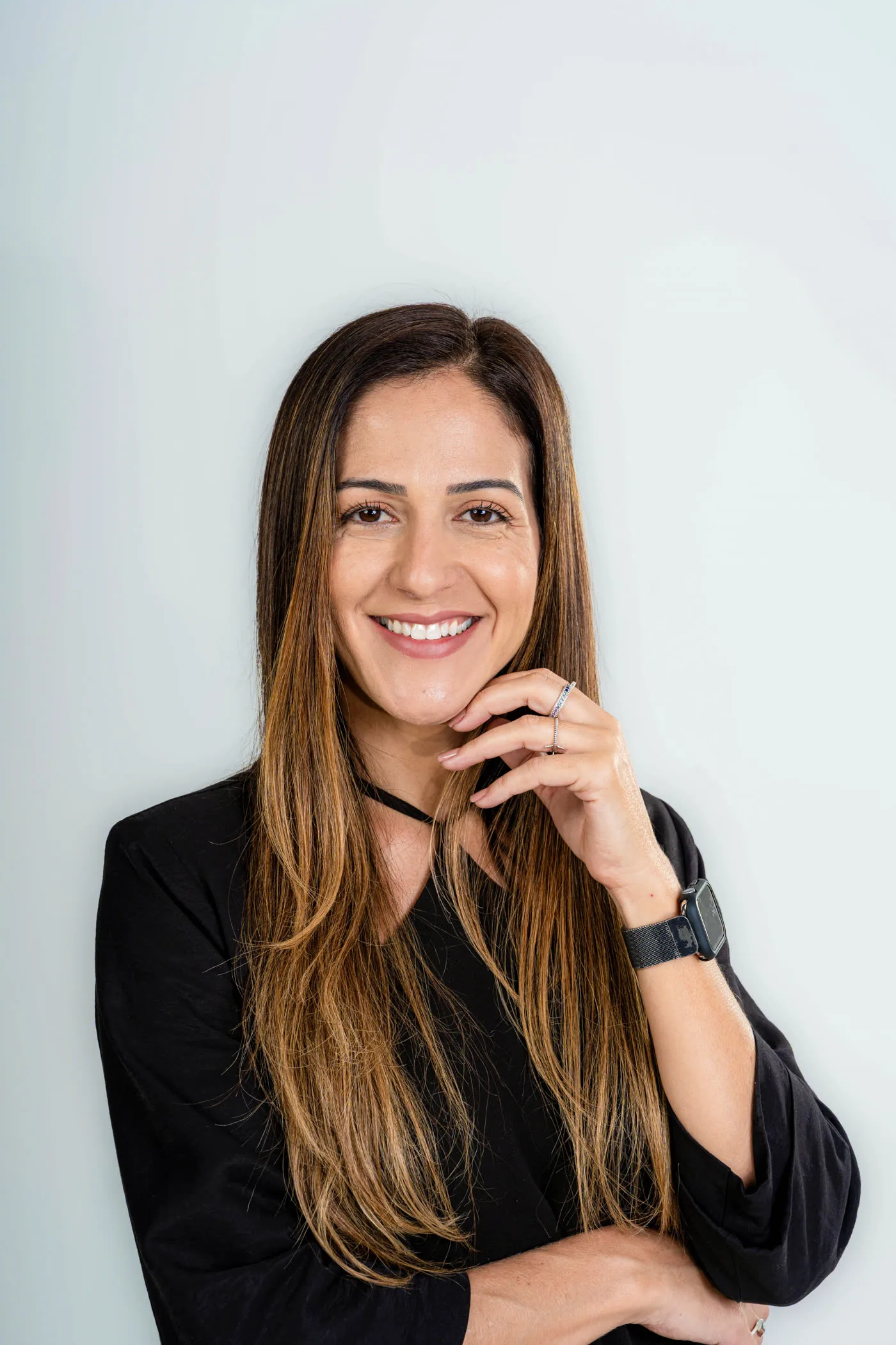 Retrato aproximado de Letícia Canedo sorrindo, com a mão apoiada no queixo